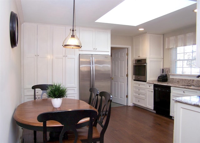 kitchen with dark wood finished floors, appliances with stainless steel finishes, light stone counters, decorative light fixtures, and white cabinetry