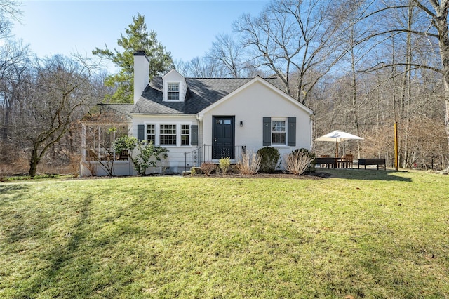 view of front of property with a shingled roof, a chimney, and a front yard