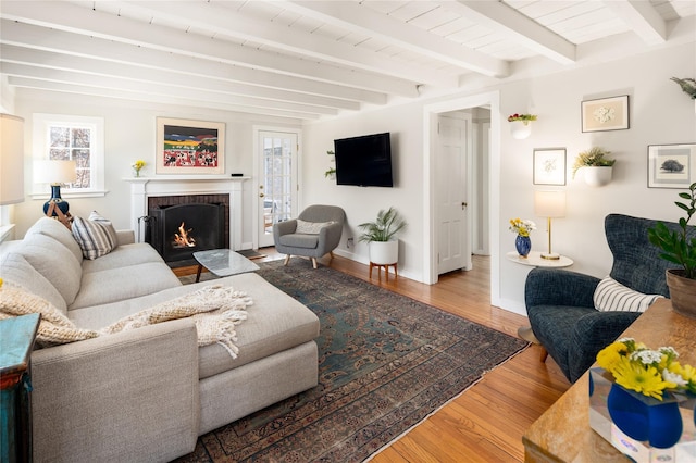 living room featuring a fireplace, wood finished floors, beam ceiling, and baseboards