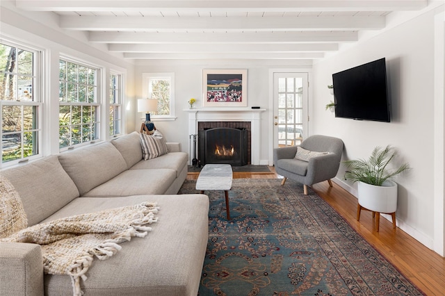 living area featuring beam ceiling, baseboards, a fireplace, and hardwood / wood-style floors