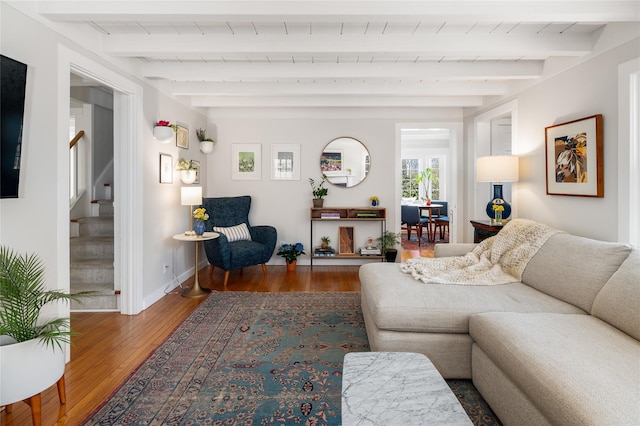 living room featuring stairway, wood finished floors, beam ceiling, and baseboards