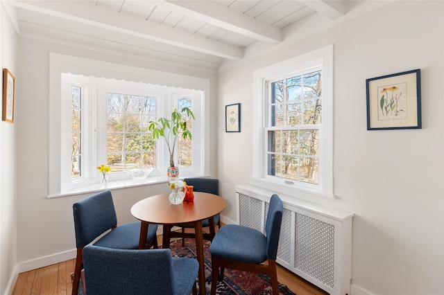 dining area with beam ceiling, baseboards, radiator heating unit, and wood finished floors