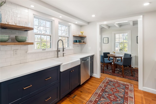 kitchen featuring dishwasher, backsplash, blue cabinetry, open shelves, and a sink