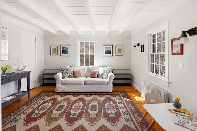 living area with radiator, beamed ceiling, baseboards, and wood finished floors