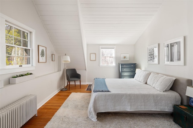 bedroom featuring radiator heating unit, baseboards, vaulted ceiling, and wood finished floors