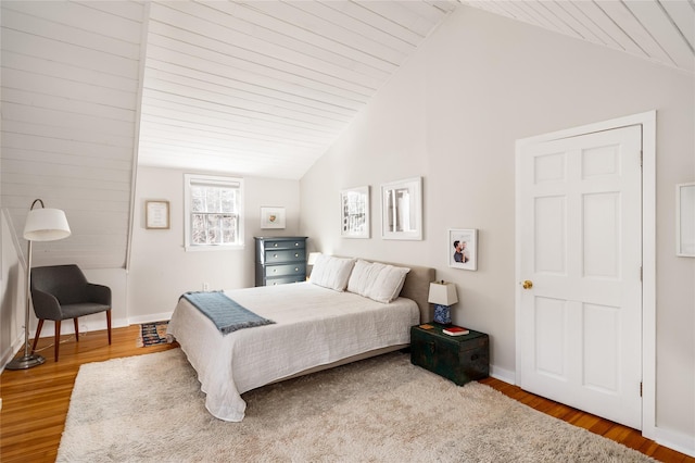 bedroom with lofted ceiling, baseboards, and wood finished floors