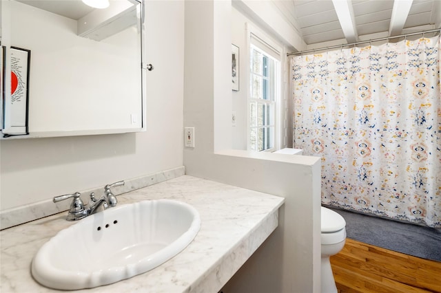 full bath featuring curtained shower, toilet, vanity, wood finished floors, and beamed ceiling