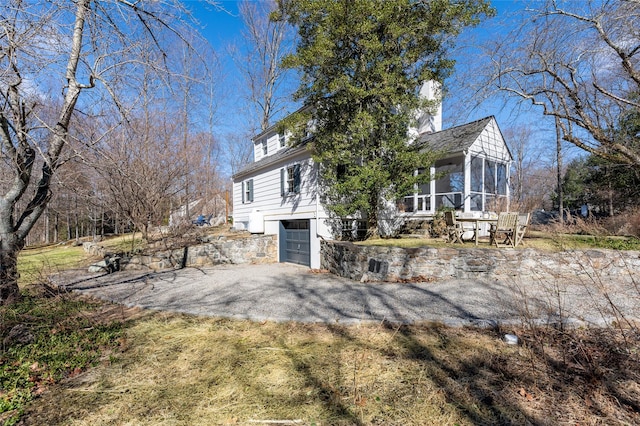 view of side of property with a garage, aphalt driveway, and a sunroom