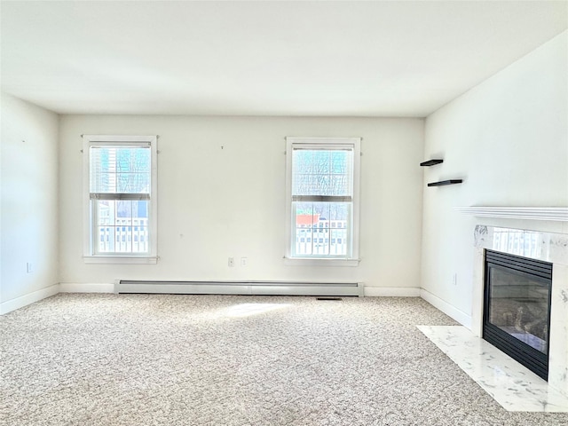 unfurnished living room featuring plenty of natural light, a premium fireplace, baseboard heating, and light colored carpet