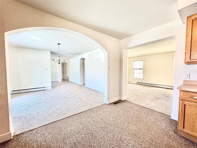 spare room featuring arched walkways, carpet flooring, baseboard heating, and an inviting chandelier