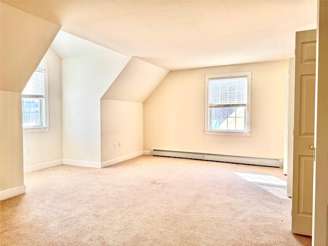 additional living space with a baseboard heating unit, light colored carpet, vaulted ceiling, and baseboards