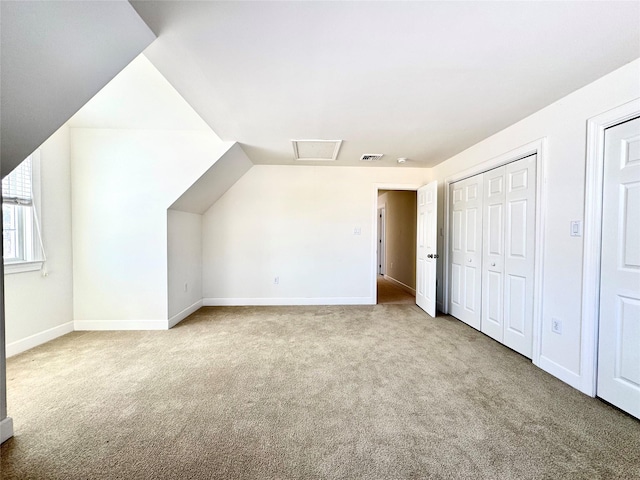 additional living space with attic access, light colored carpet, visible vents, and baseboards