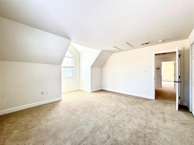 additional living space featuring attic access, lofted ceiling, visible vents, and light colored carpet