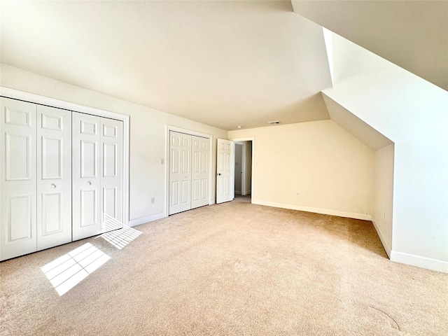 additional living space featuring light carpet, visible vents, and baseboards