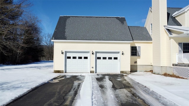 snow covered garage with driveway