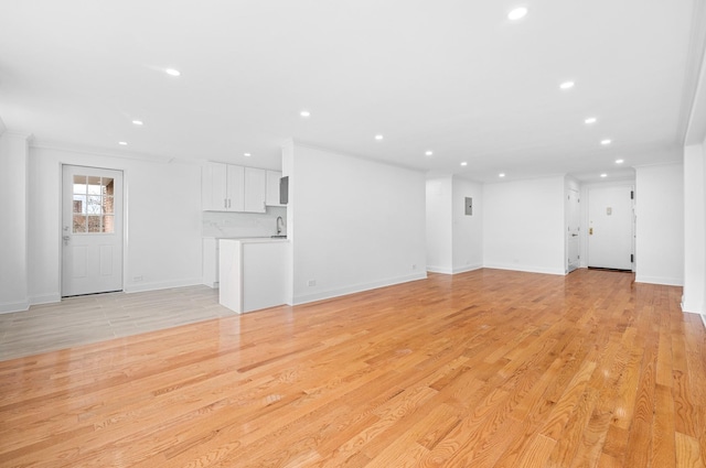 unfurnished living room featuring light wood finished floors, baseboards, and recessed lighting