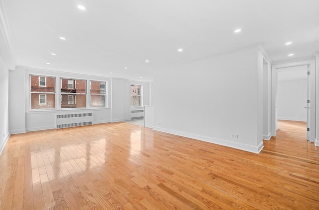 unfurnished living room featuring recessed lighting, baseboards, ornamental molding, light wood finished floors, and radiator heating unit