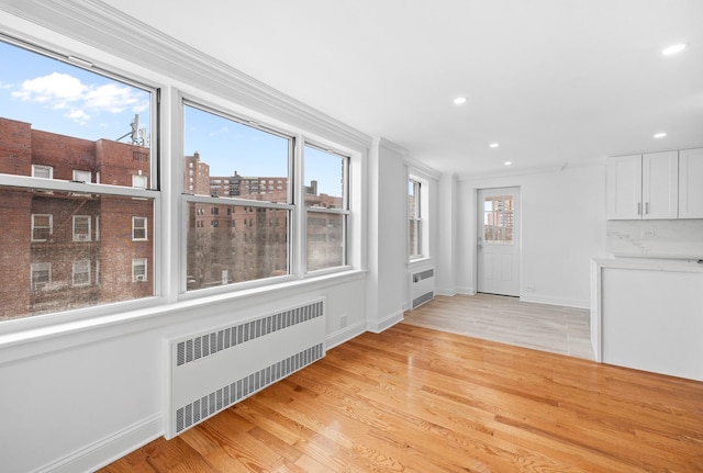 interior space with light wood-type flooring, radiator heating unit, a city view, and recessed lighting