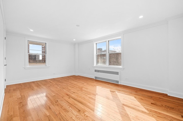 unfurnished room with ornamental molding, radiator, light wood-style floors, and baseboards