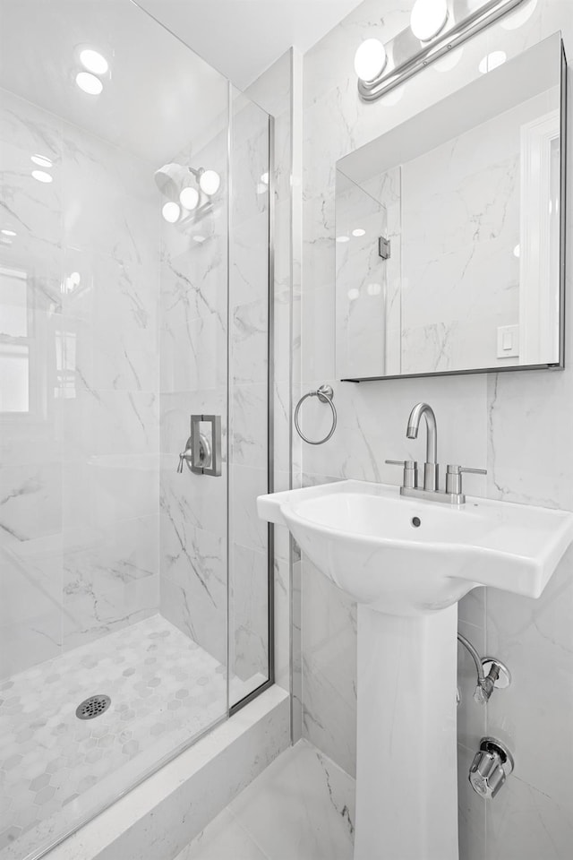 full bathroom featuring tile walls, a sink, backsplash, and a marble finish shower