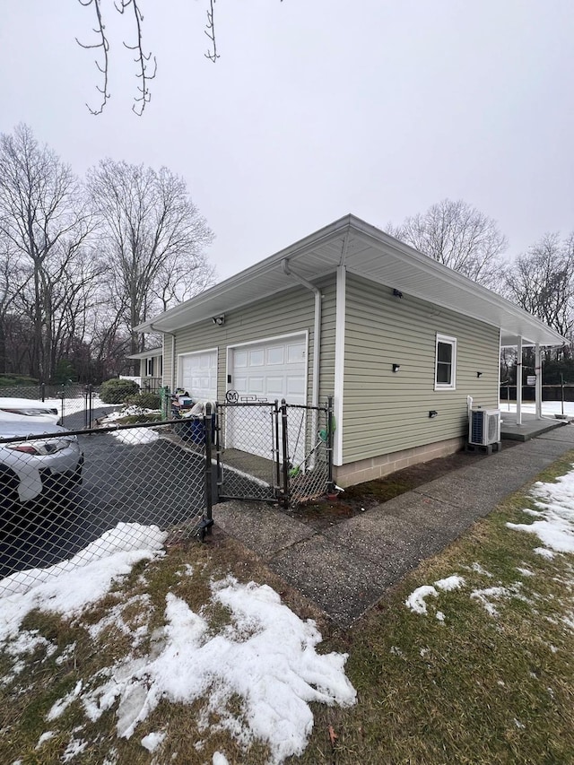 snow covered property with a garage, a gate, and fence