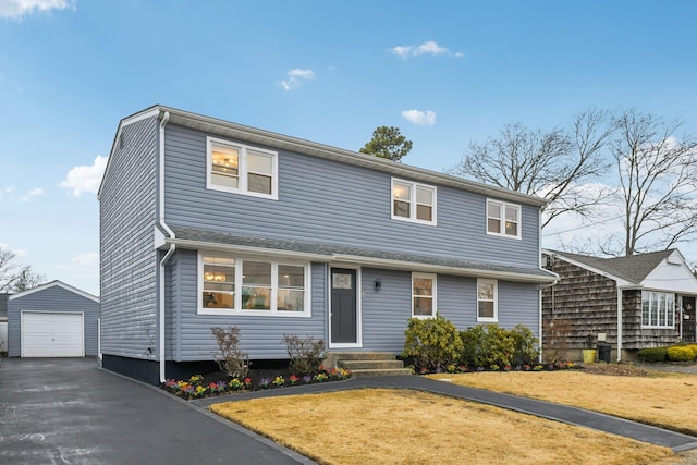 view of front of home featuring an outbuilding, driveway, a front lawn, and a garage