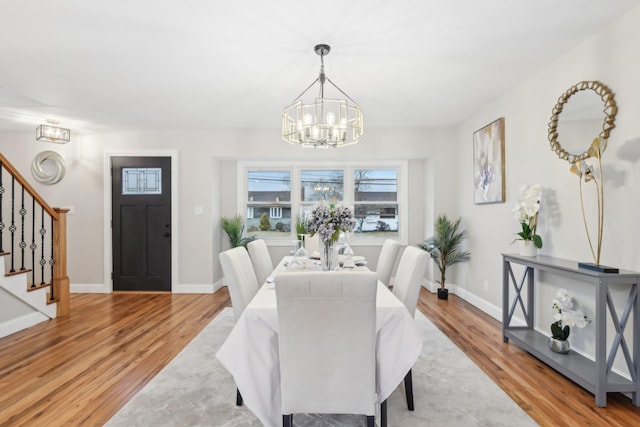 dining area featuring stairs, baseboards, wood finished floors, and an inviting chandelier