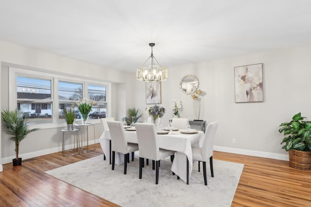 dining space with a notable chandelier, baseboards, and wood finished floors