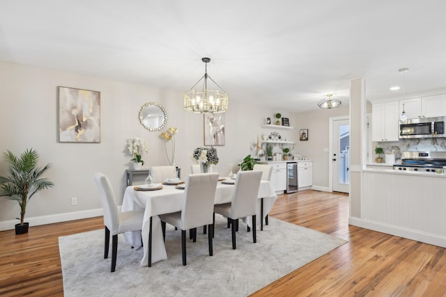 dining room featuring light wood-type flooring, beverage cooler, baseboards, and an inviting chandelier