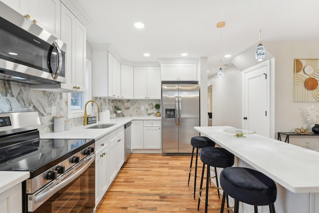 kitchen featuring stainless steel appliances, a breakfast bar, light countertops, and a sink