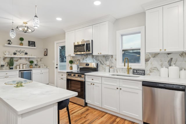 kitchen with light wood-style flooring, a sink, white cabinets, appliances with stainless steel finishes, and open shelves