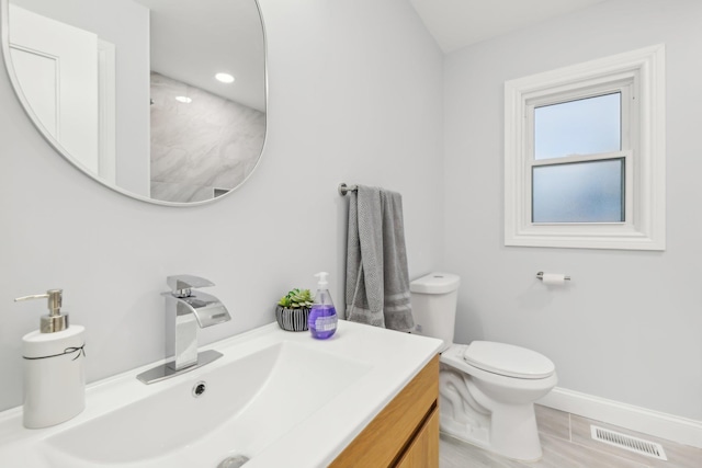 bathroom with toilet, vanity, visible vents, and baseboards