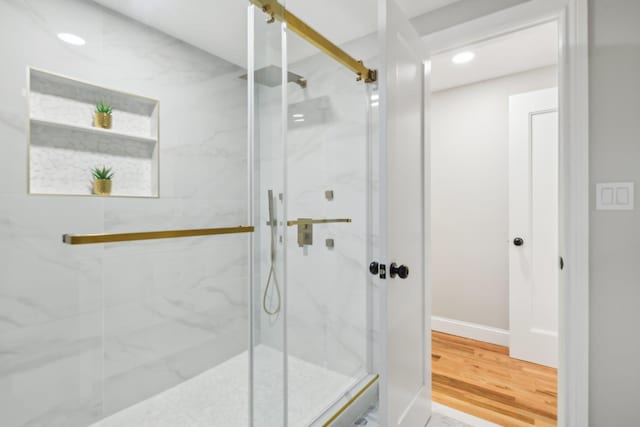 full bath featuring baseboards, wood finished floors, a marble finish shower, and recessed lighting