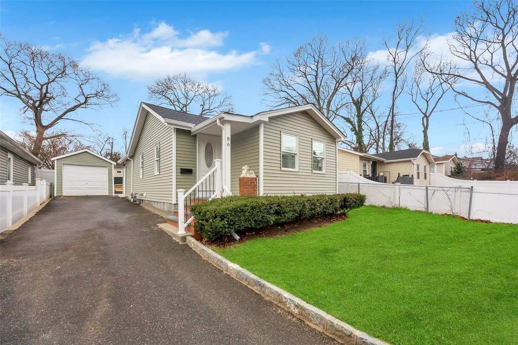 86 Eastview Rd, Ronkonkoma, NY 11779 - view of front of house featuring an outdoor structure, fence, aphalt driveway, a detached garage, and a front lawn