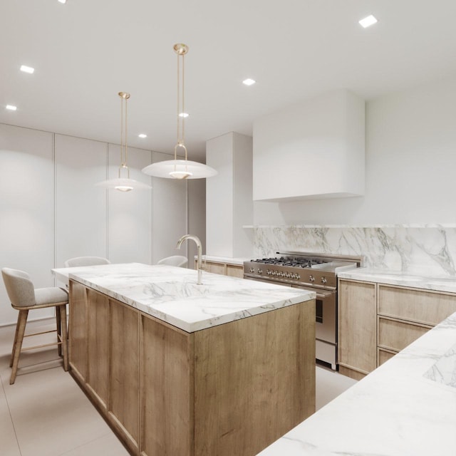 kitchen featuring a kitchen island with sink, light stone counters, and high end range