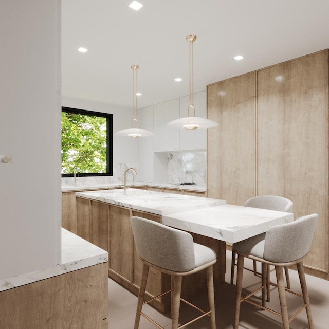 kitchen with tasteful backsplash, light stone countertops, an island with sink, and modern cabinets