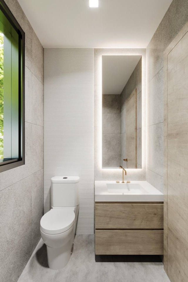 bathroom with concrete floors, vanity, toilet, and tile walls