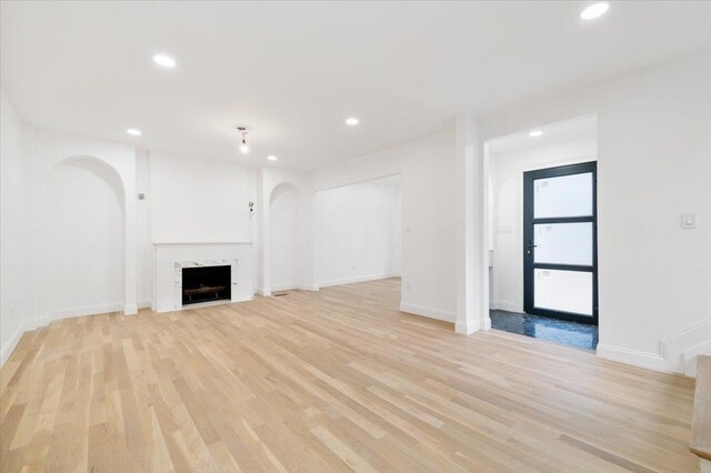 670 Emerson St, Woodmere, NY 11598 - unfurnished living room featuring arched walkways, recessed lighting, light wood-style floors, and a premium fireplace