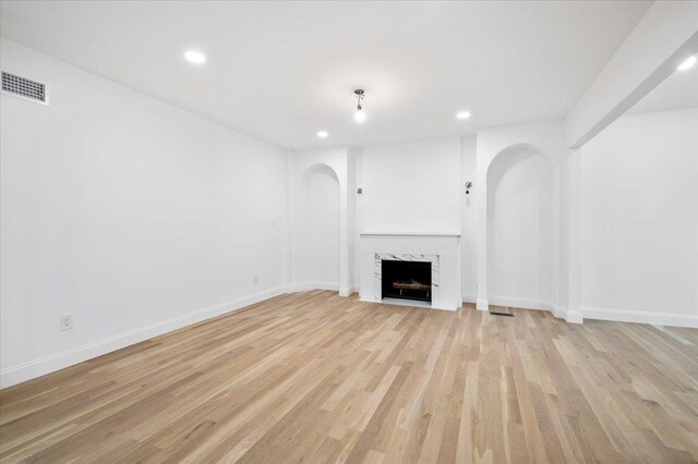 670 Emerson St, Woodmere, NY 11598 - unfurnished living room featuring arched walkways, recessed lighting, light wood-type flooring, and a premium fireplace