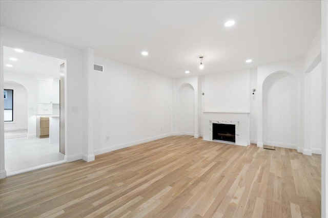 670 Emerson St, Woodmere, NY 11598 - unfurnished living room with arched walkways, light wood-type flooring, recessed lighting, and a premium fireplace