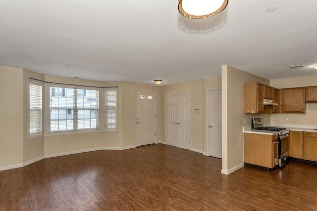 kitchen with brown cabinets, dark wood-style flooring, light countertops, under cabinet range hood, and gas stove