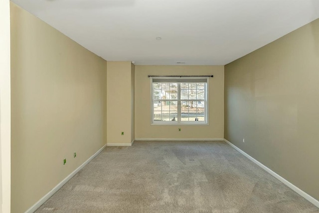 empty room featuring light carpet and baseboards