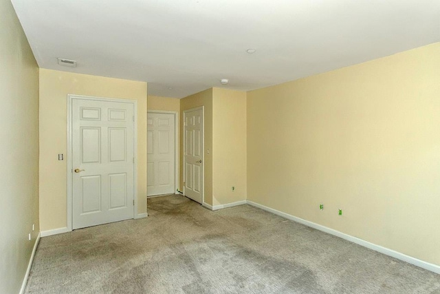 spare room featuring visible vents, baseboards, and light colored carpet