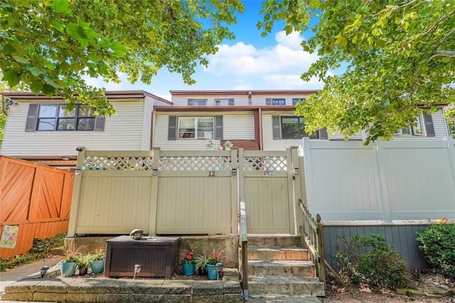 view of front facade featuring a gate, fence, and central AC unit