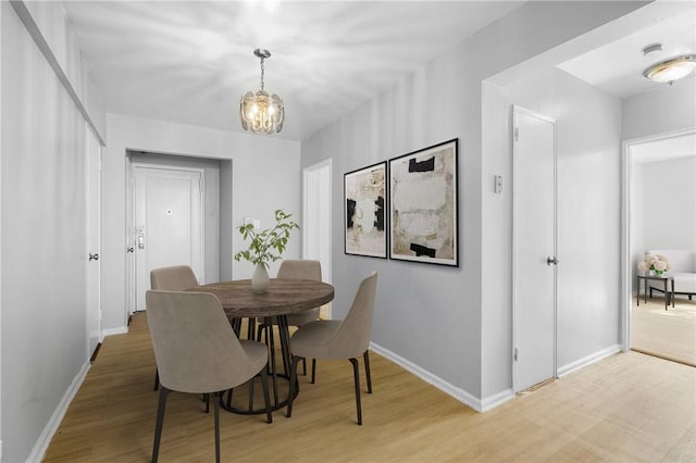 dining space featuring a chandelier, light wood-type flooring, and baseboards