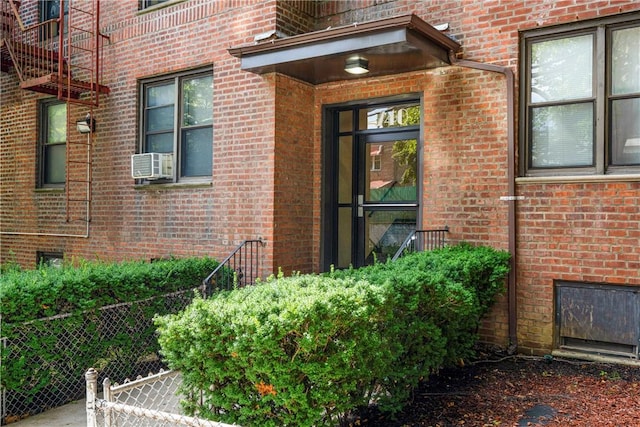 property entrance with fence, cooling unit, and brick siding