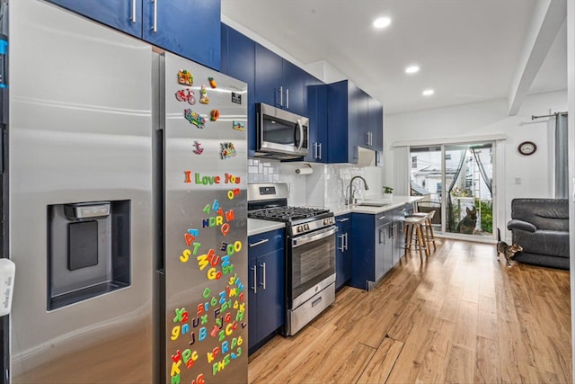 kitchen with decorative backsplash, light wood-style flooring, blue cabinets, stainless steel appliances, and light countertops