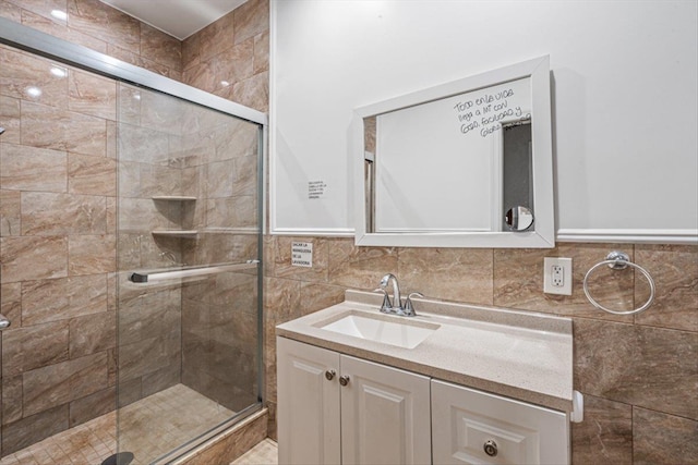 full bathroom with a stall shower, vanity, and tile walls