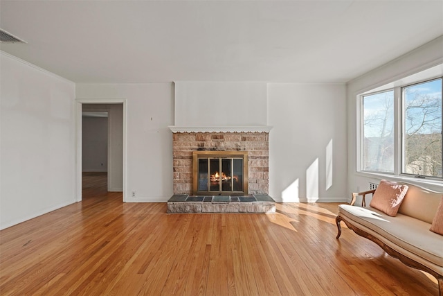 unfurnished living room with light wood-style floors, baseboards, a fireplace, and visible vents