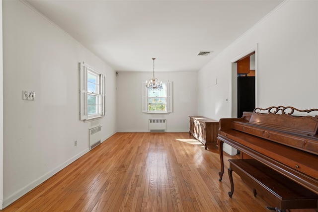 sitting room featuring baseboards, light wood finished floors, visible vents, and radiator